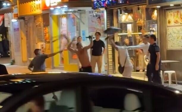 兩名男子分別持膠櫈及鐵櫈,夾擊一名赤膊赤腳的男子。(FB/車cam L(香港群組))