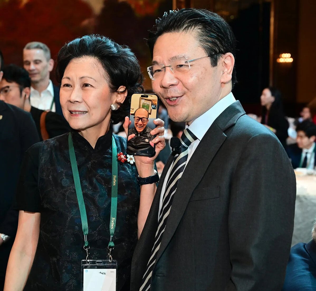 李嘉誠(電話中)與周凱旋(左)及黃循財(右)隔空同框。(《福布斯》圖片)