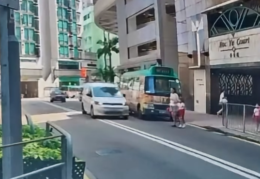 車Cam直擊︱羅便臣道一名45歲婦人與5歲女兒落小巴後橫過馬路時,一輛客貨車涉在雙白線爬頭越過小巴前行,結果將母女撞倒。(影片截圖)