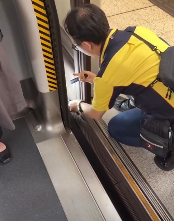 一名港鐵男職員趁列車短暫停站,用萬能夾伸入列車與月台之間的路軌罅隙,不足10秒便成功夾回乘客掉下的一隻蘋果AirPods耳機。(影片截圖)