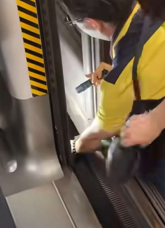 一名港鐵男職員趁列車短暫停站,用萬能夾伸入列車與月台之間的路軌罅隙,不足10秒便成功夾回乘客掉下的一隻蘋果AirPods耳機。(影片截圖)