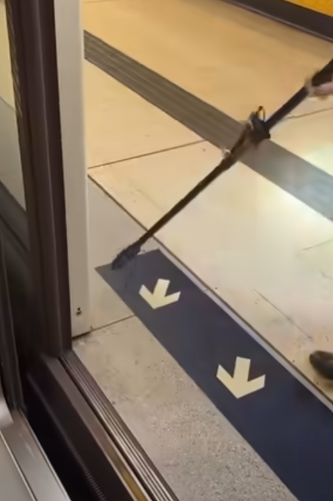 一名港鐵男職員趁列車短暫停站,用萬能夾伸入列車與月台之間的路軌罅隙,不足10秒便成功夾回乘客掉下的一隻蘋果AirPods耳機。(影片截圖)