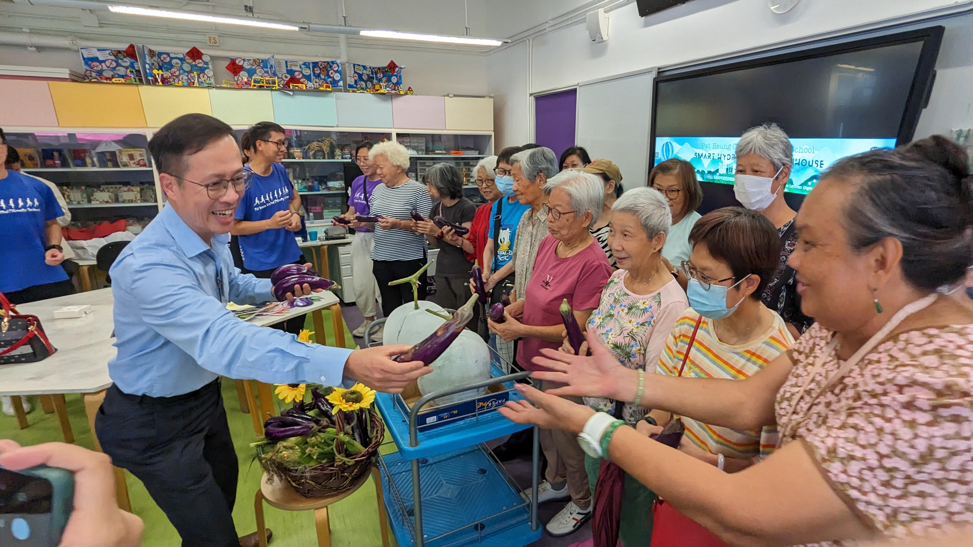 煤氣公司策略及創新總監暨商務總監—香港公用業務馮文傑(左)於八鄉中心小學溫室開幕當天,送贈煤氣公司慈善農莊的農作物予參與活動的長者。