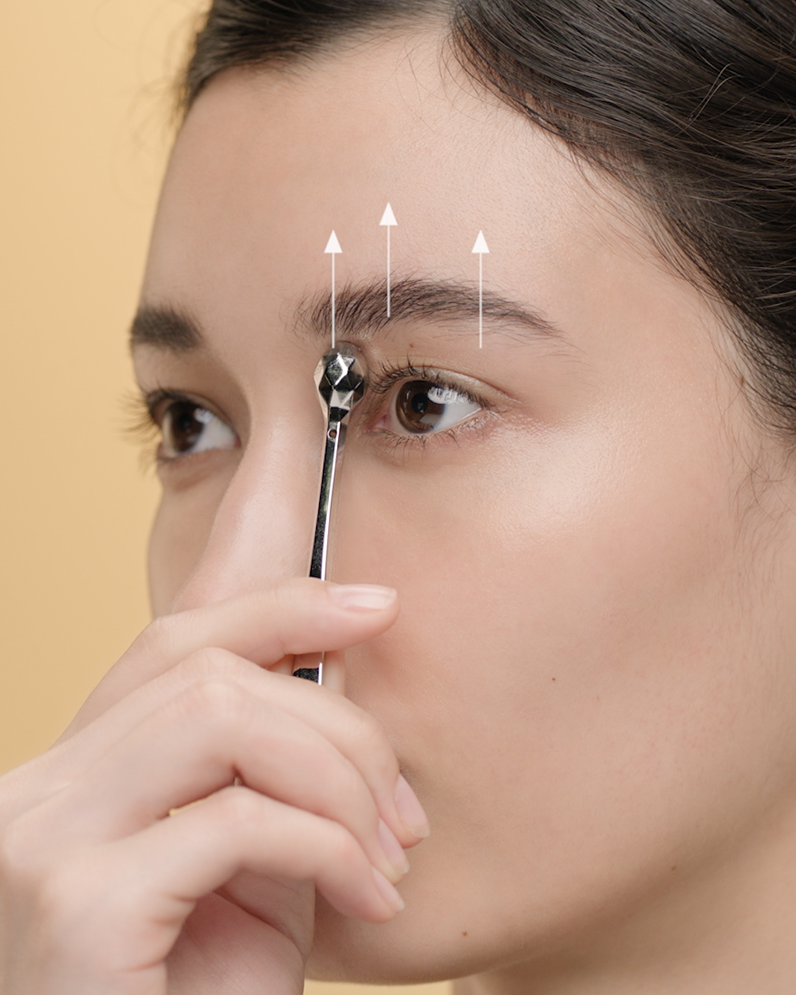 4. 收緊上眼瞼：將鉑金眼部按摩棒從眉毛下方輕柔地向上滑動，同時輕力按壓。每邊重複三次。