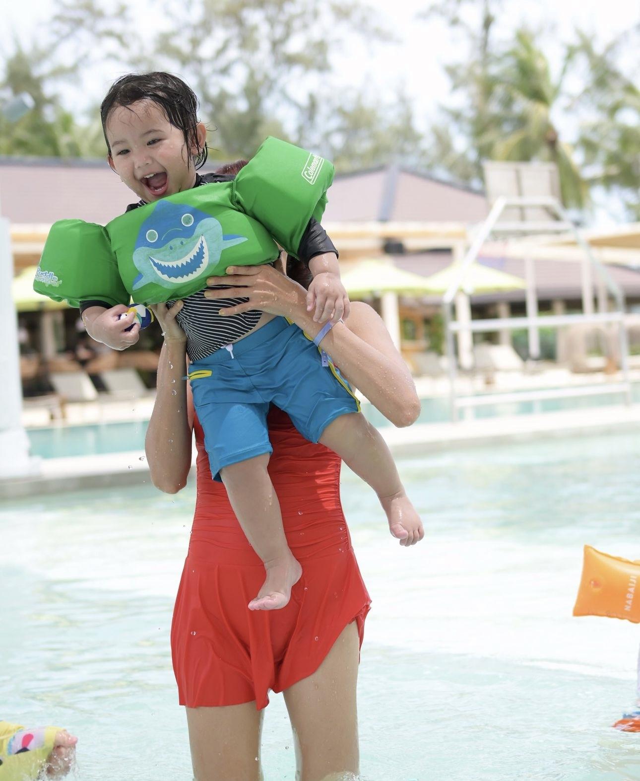Grace穿上橙色一件頭泳衣,並抱住細仔Carlos在嬉水。