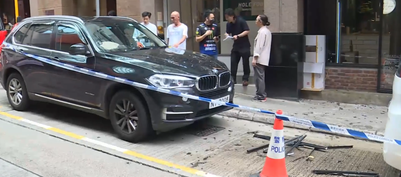 中環士丹利街50號一幢商業大廈有鋁窗從高處墜下,3輛私家車及一名女途人被碎片濺中,女子手傷經救護員治理後毋須送院。(有線新聞畫面)