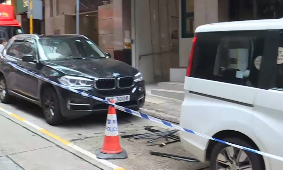 中環士丹利街50號一幢商業大廈有鋁窗從高處墜下,3輛私家車及一名女途人被碎片濺中,女子手傷經救護員治理後毋須送院。(有線新聞畫面)