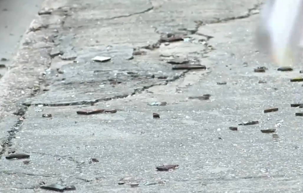 中環士丹利街50號一幢商業大廈有鋁窗從高處墜下,3輛私家車及一名女途人被碎片濺中,女子手傷經救護員治理後毋須送院。(有線新聞畫面)