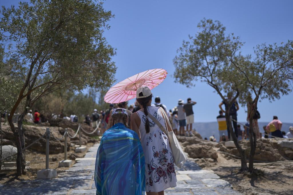 希臘旅遊勝地雅典衛城陽光猛烈,有遊客撐傘降溫。(美聯社)