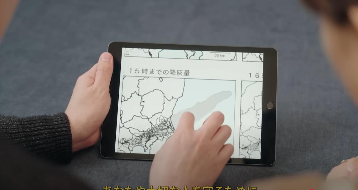 AI模擬富士山大爆發影片中,居民查看火山灰降量相關資訊。(互聯網)