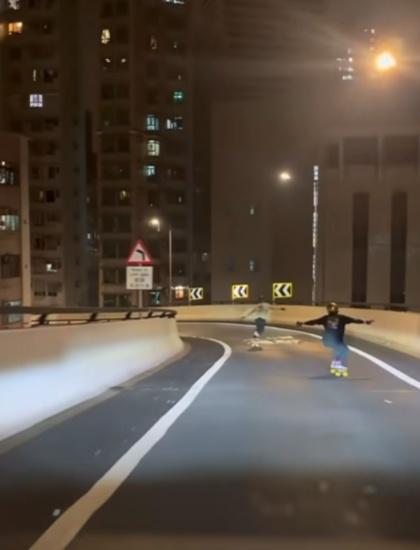 兩名身穿黑白衣服的男子,戴有頭盔等裝備,在山道天橋狂飆落斜。(FB/車cam L(香港群組))