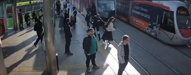 女子沒察覺有電車駛至便過馬路,所幸車站保安員及時伸手拉她一把。(互聯網)