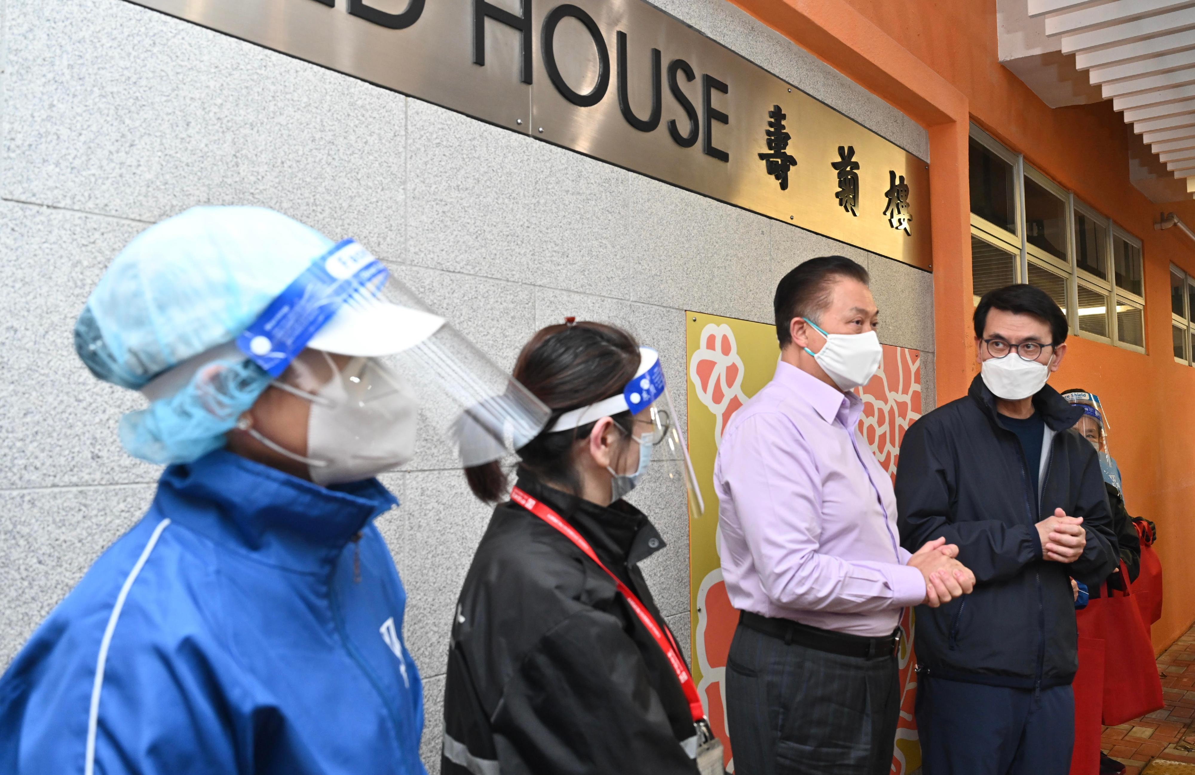 邱騰華(右一)下午到蘇屋邨，派發防疫物資予前線人員。 (政府圖片)