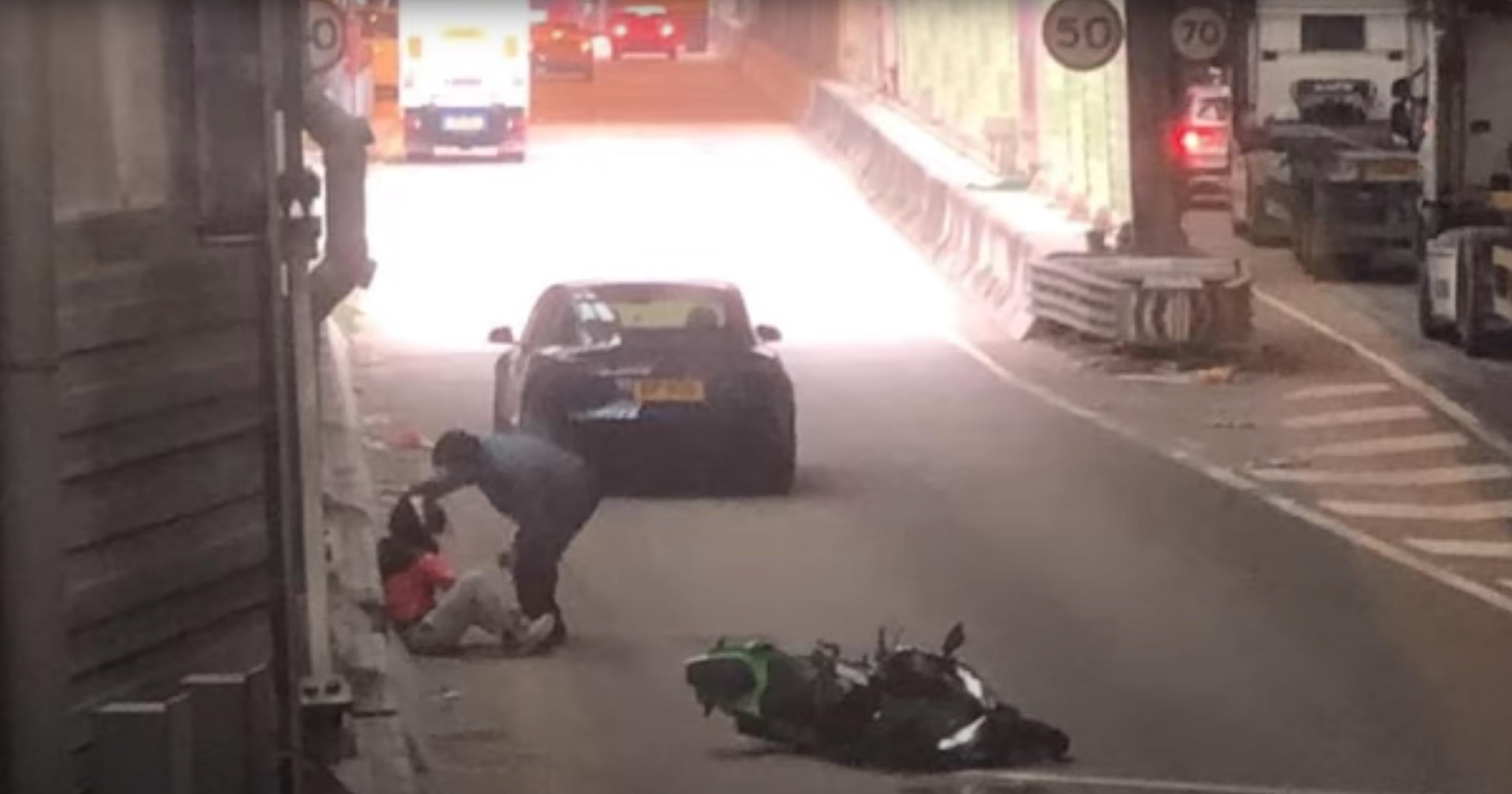 電單車司機事後坐在路旁，疑似Tesla司機在旁安慰。(網片截圖)