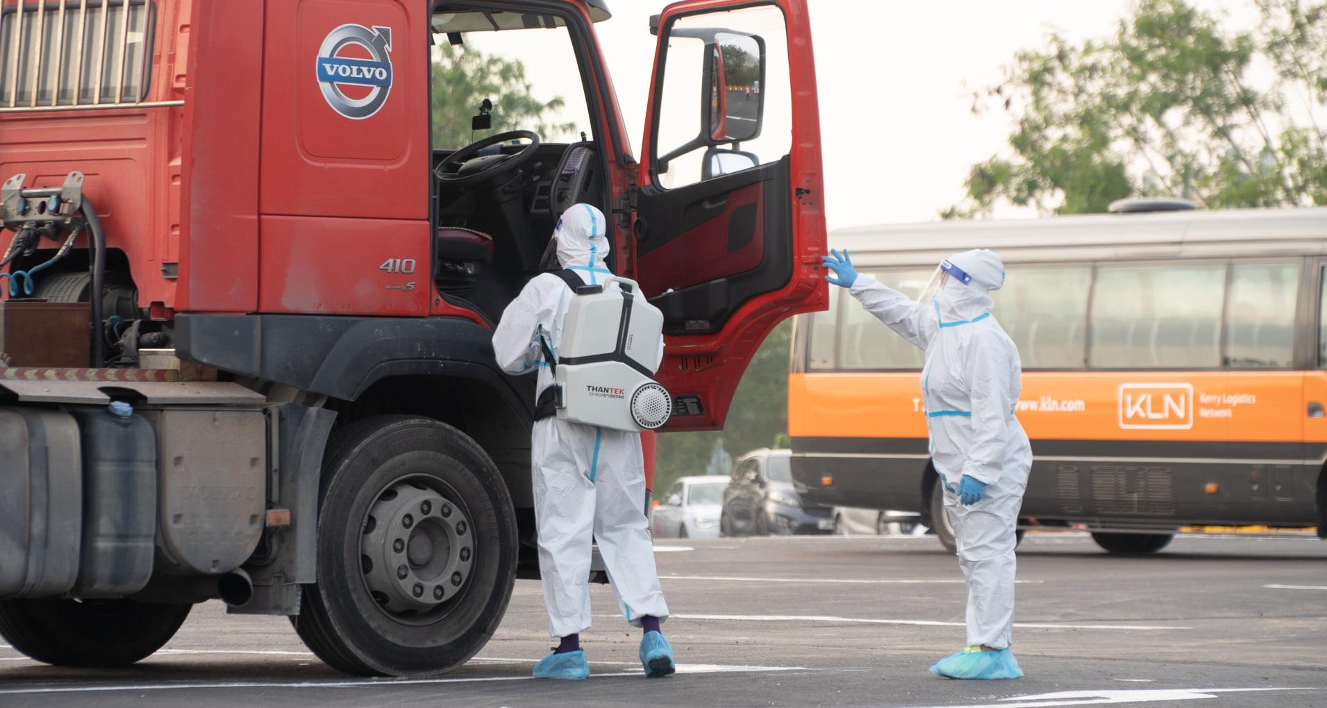 身穿全副保護衣的職員在新田錦壆路貨物接駁場，為到場貨櫃車消毒。(運房點線面FB)