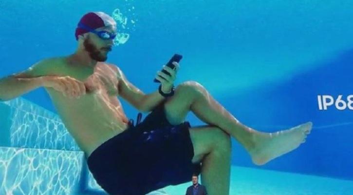 廣告中，模特兒在水裡使用手機。(互聯網)