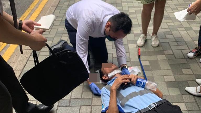 一名著地盤衫的中年男子跌倒在地上，現場人士為他進行急救。(香港突發事故報料區@fb圖)