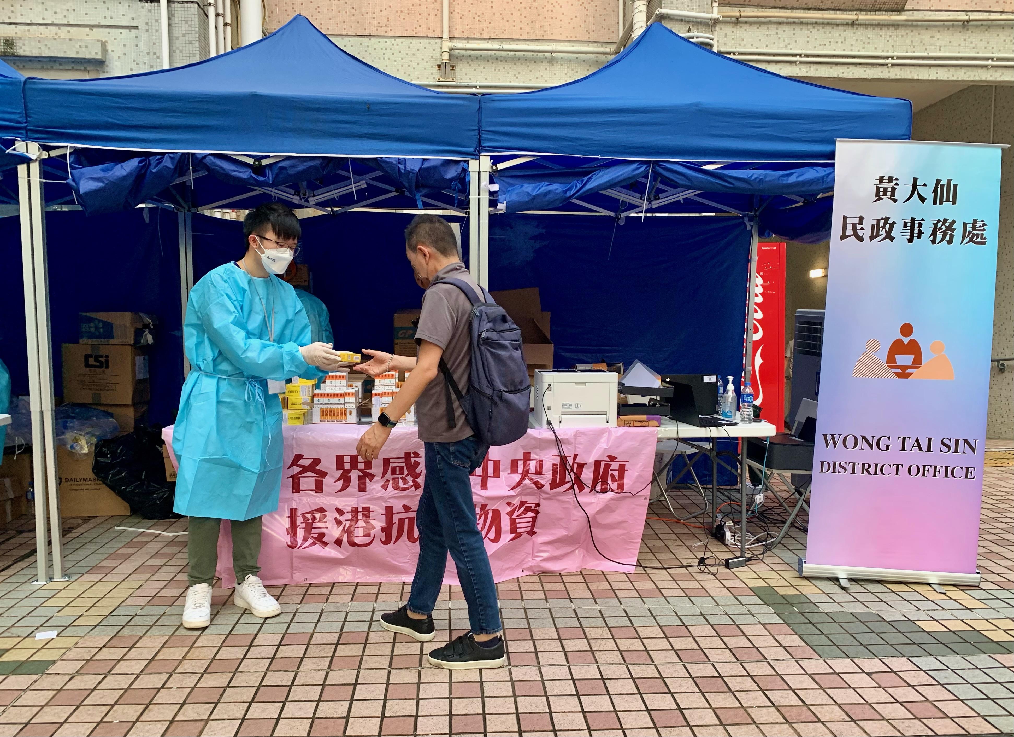 工作人員在「受限區域」內向受限人士派發由中央人民政府捐贈或支援特區政府採購的抗疫中成藥。
