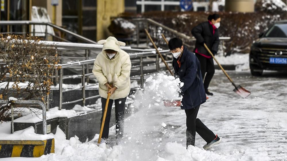 烏魯木齊大雪，民眾昨在街頭清理積雪。當地陸續恢復正常生活、生產。(中新社)