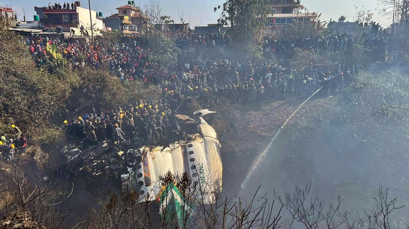 救援人員在客機殘骸搜救，大批居民聚集圍觀。(美聯社)