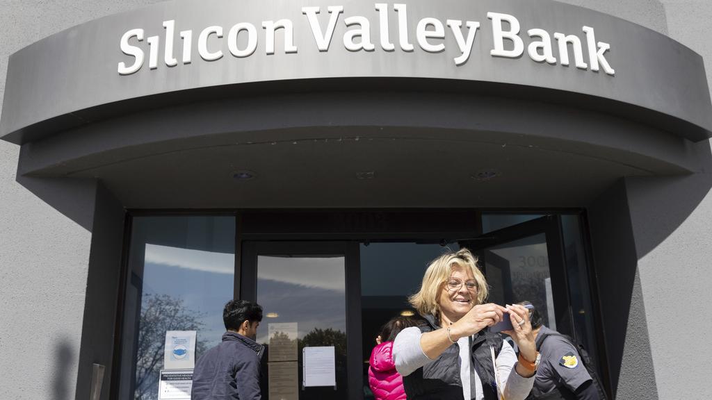 矽谷銀行加州聖克拉拉分行周一重開，有民眾在門外開心自拍。(美聯社)