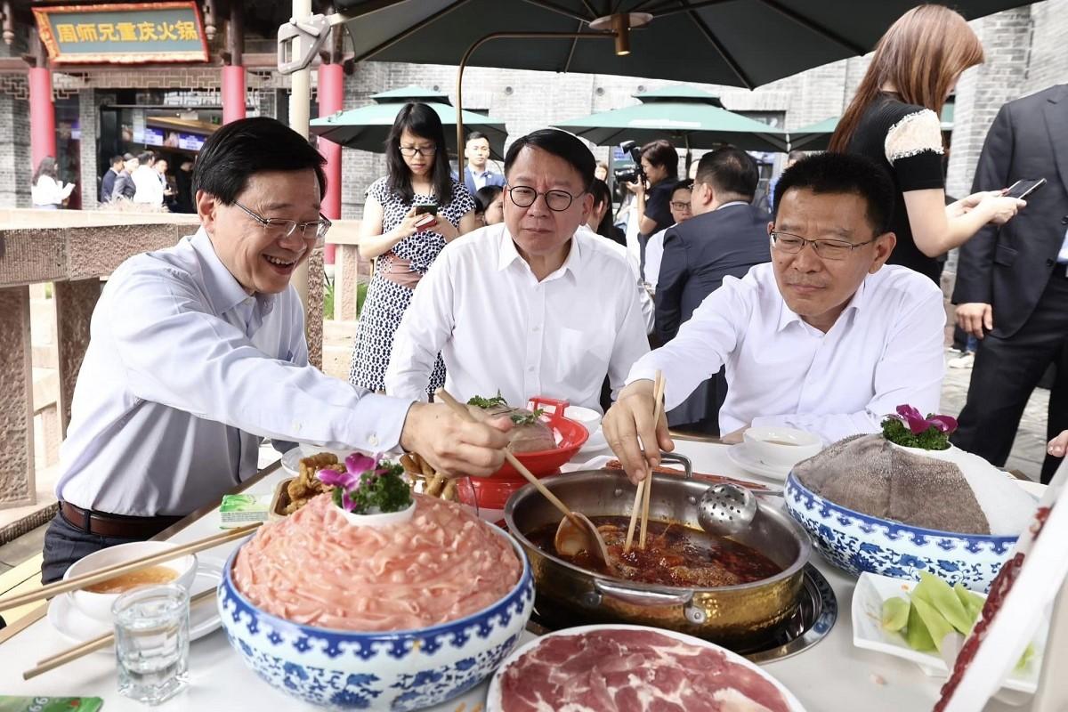 李家超(左)和港府代表團參觀磁器口古鎮，並品嚐正宗的重慶麻辣火鍋；中為香港政務司司長陳國基。(李家超FB)