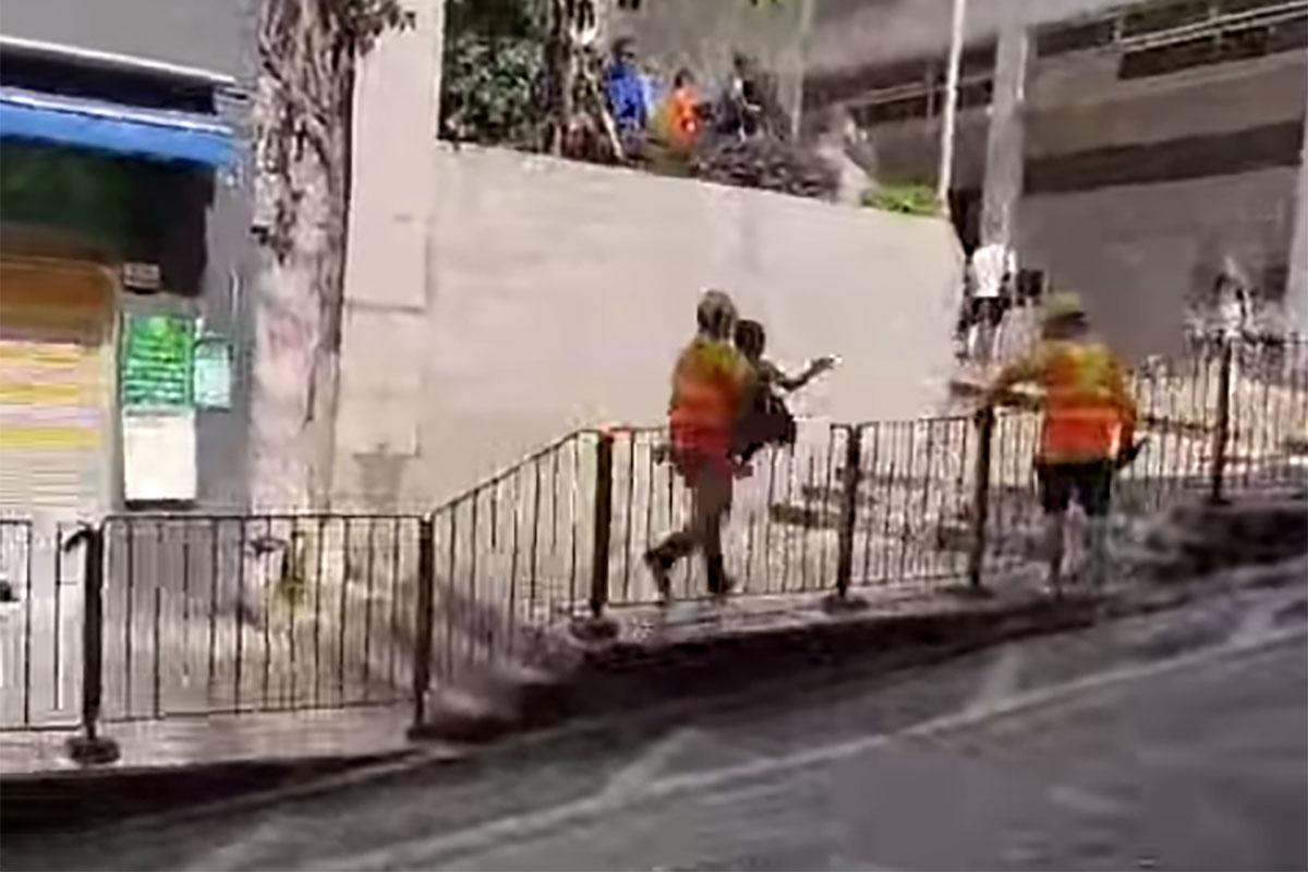 西營盤有婆婆被困爆水管「激流」，地盤工人見狀上前「公主抱」助脫困。(網民Ca Yue@FB群組「西環變幻時」影片截圖)