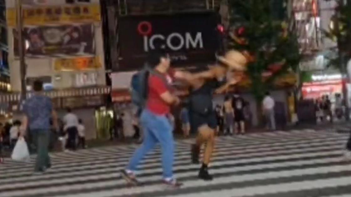 美國網紅在秋葉原馬路跳舞期間，被一男子打甩帽子。(影片截圖)