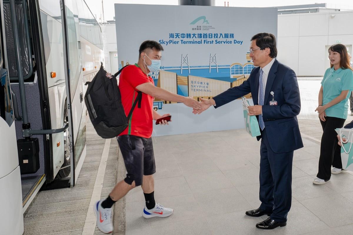 林天福(右)在海天中轉大樓歡迎首批轉機旅客。(機管局圖片)