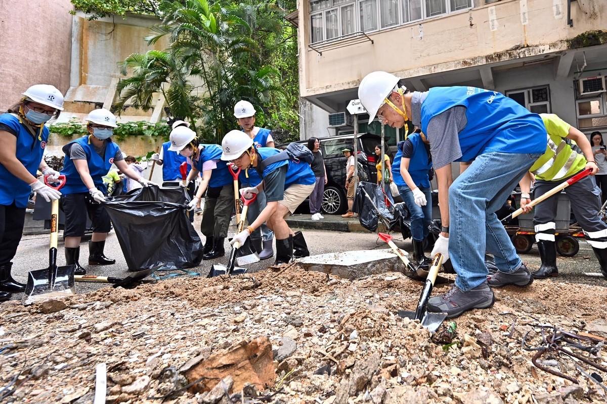 公務員事務局組成一隊30人的政府應急隊，到鰂魚涌街清理路面，常秘梁卓文(右一)亦有親自揸起鐵鏟清垃圾。(公務員事務局FB)
