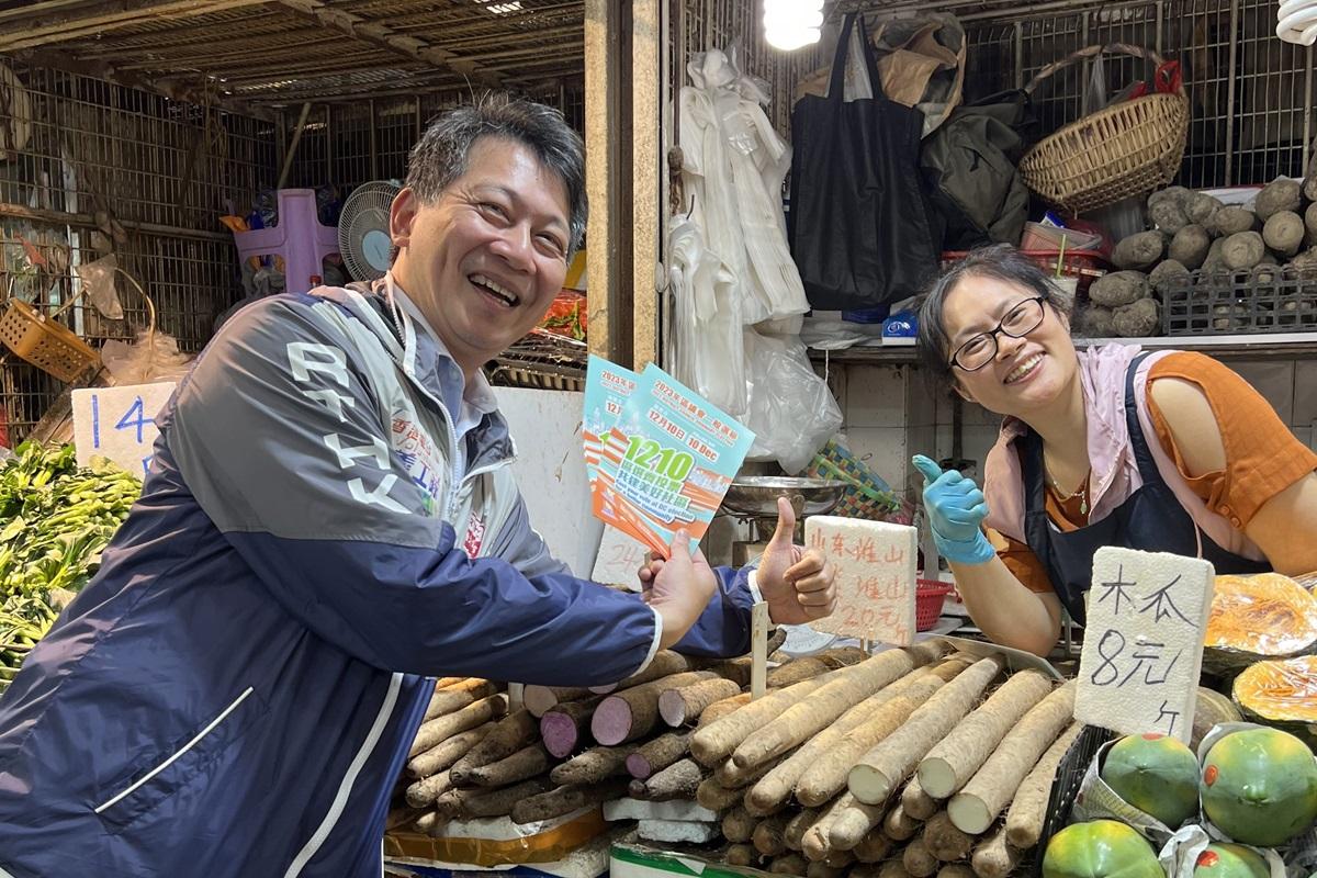 張國財(左)向屯門商戶派發區議會選舉宣傳單張。(港台提供)