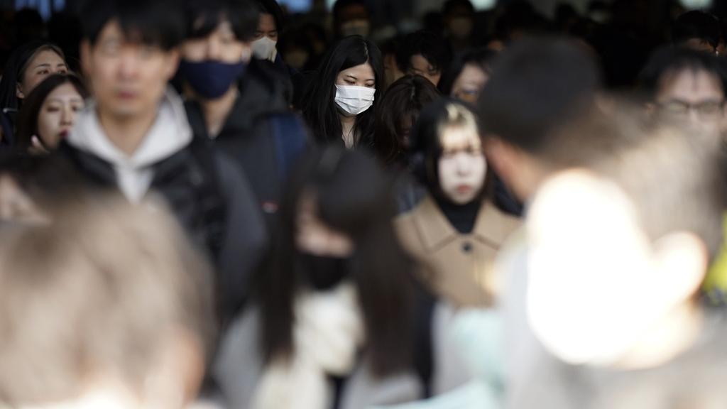 日本關東地區周四吹起春天從南方吹來的第一陣強風(春一番)。圖為東京民眾周三在繁忙時間出勤。(美聯社)