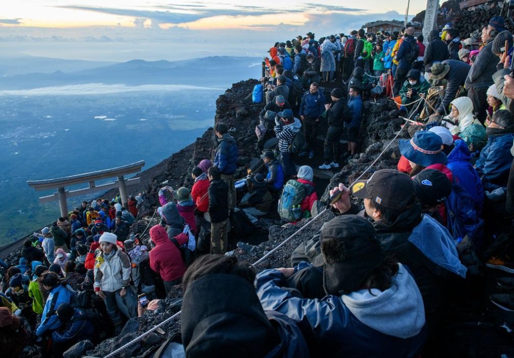 圖為大批遊客登上富士山頂觀看日出。(互聯網)