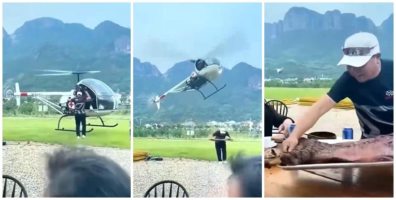 一架印有紅十字會標誌的直升機飛到浙江郊外，向一群正在野外圍坐桌前用餐的人士送上一盤「烤全羊」外賣。(影片截圖)