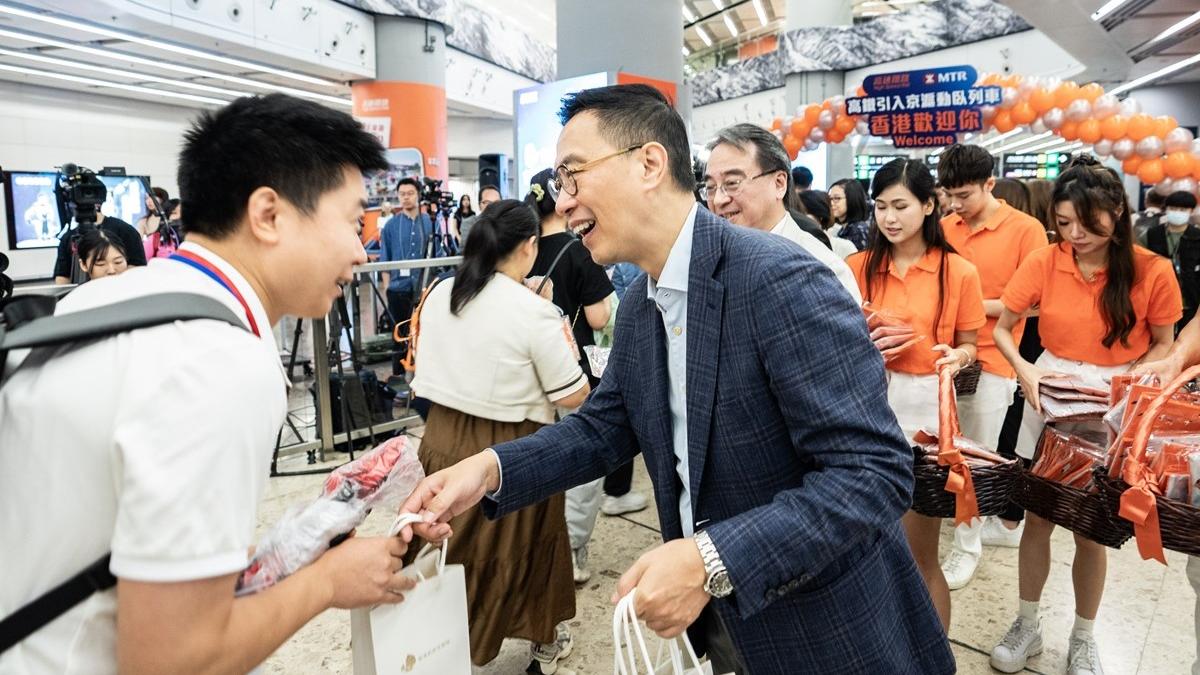 楊潤雄(右)向抵港旅客送上旅發局紀念品。(中新社)