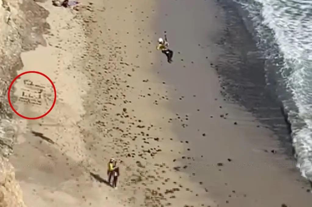 男子在沙灘上用石頭砌出「HELP」大字，獲幸運之神眷顧，最終由兩名救援人員協助脫困。(互聯網)