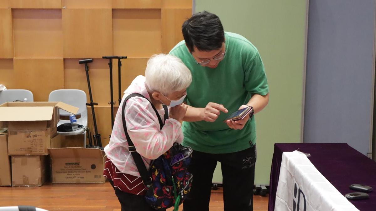 港專的青年數碼義工協助長者下載手提電話應用程式。(林嘉瑩攝)