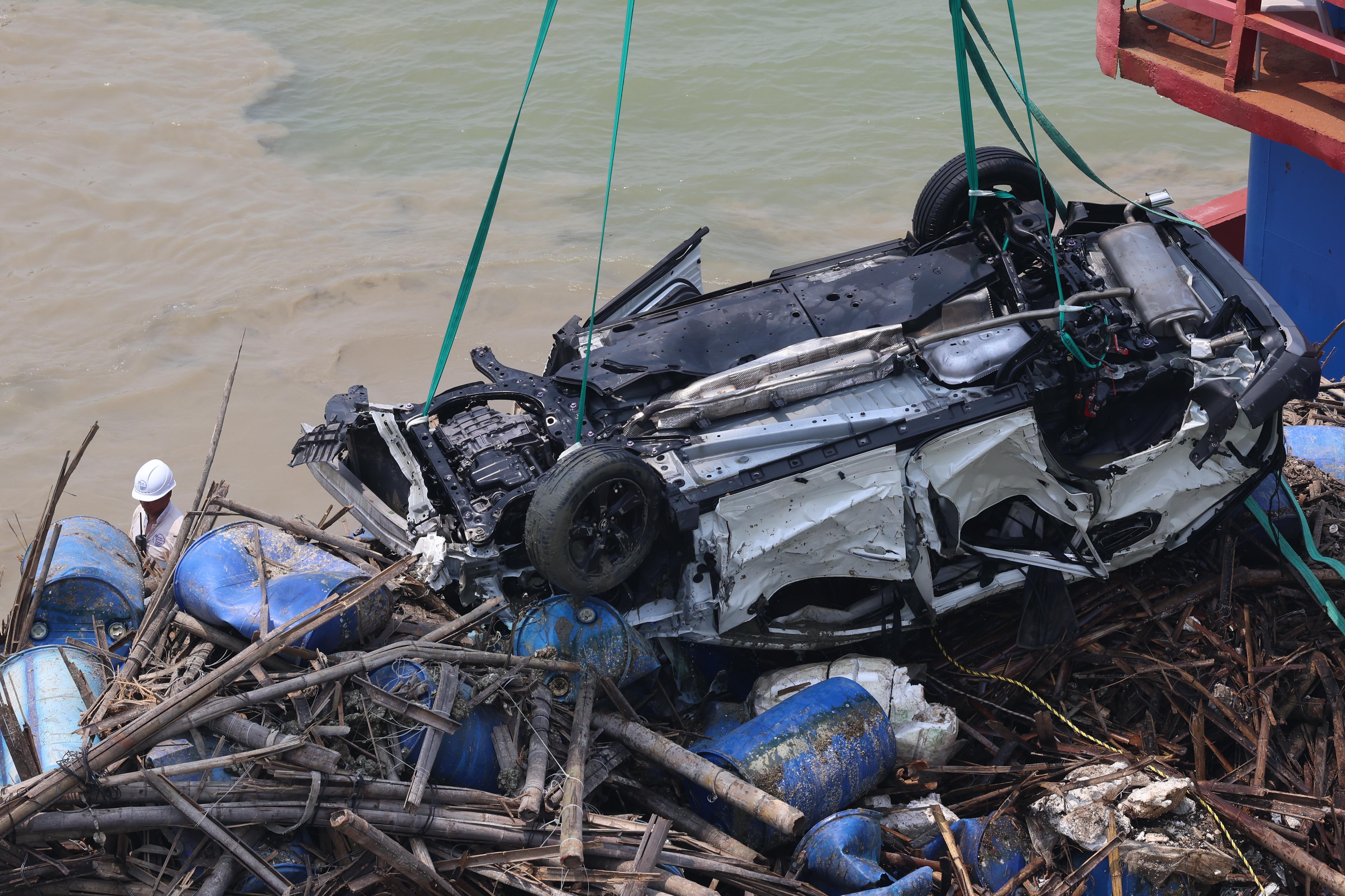 吊臂躉船在大橋附近的位置，用鋼纜把私家車由海中吊起，放上躉船運走。