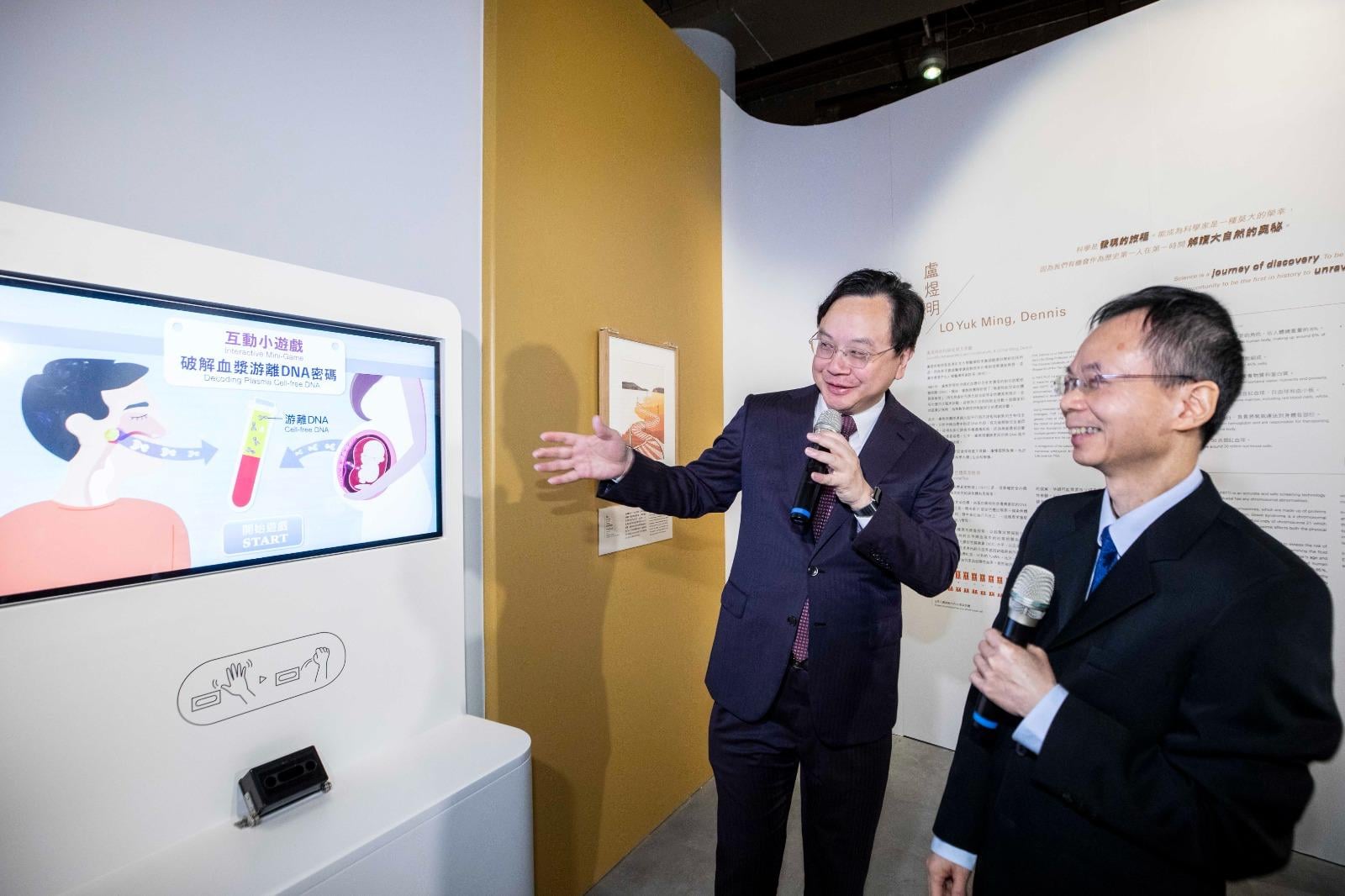 盧煜明教授(左) 介紹展覽中的互動遊戲，讓參觀者理解「無創性胎兒染色體異常檢測」的原理。（未來科學大獎圖片）