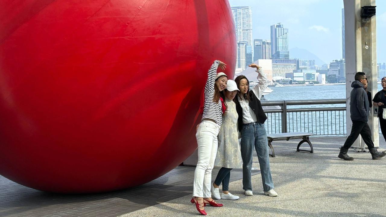 有人擺出不同姿勢與「紅球」合照。（港台圖片）