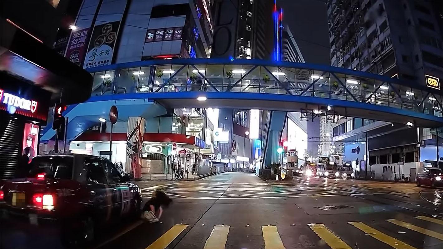 銅鑼灣有女子過馬路衝燈尾時不幸跣腳墮地，幸駛至的士及時煞車未有輾過雙腿。(網上影片截圖)