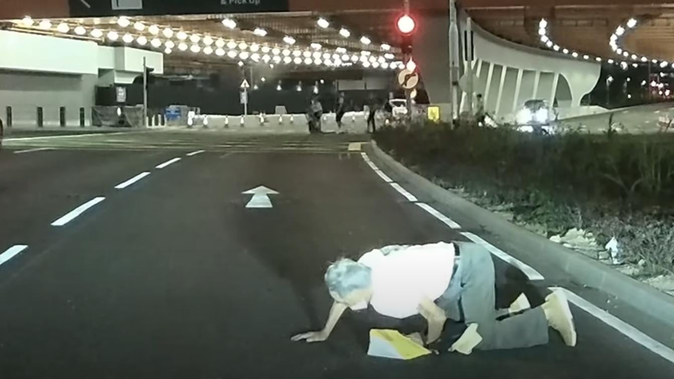 啟德體育園外老翁疑跌傷爬出馬路，好心司機「護駕」扶過路。（YouTube影片截圖）
