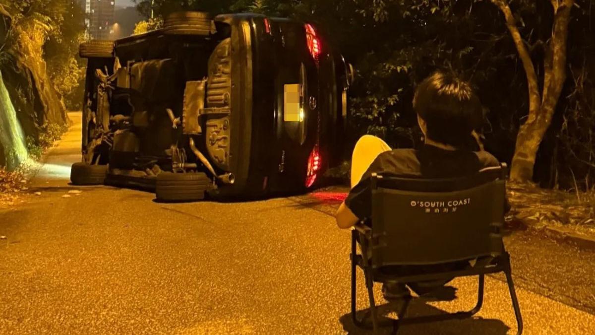 有司機在飛鵝山兜風後遇上失事車輛攔路，只好苦中作樂取出露營櫈坐在路上「打卡」等候處理。(Threads圖片)