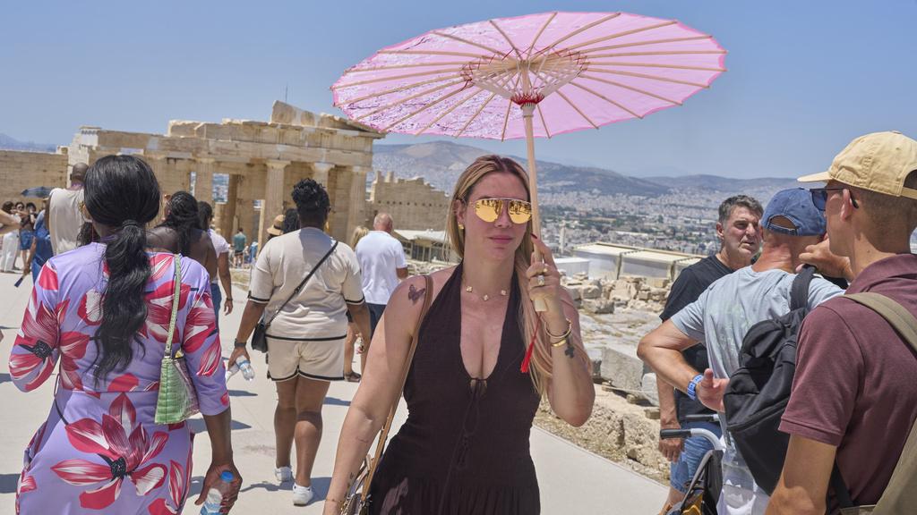 希臘旅遊勝地雅典衛城炎熱，有遊客撐傘遮擋猛烈陽光。(美聯社)
