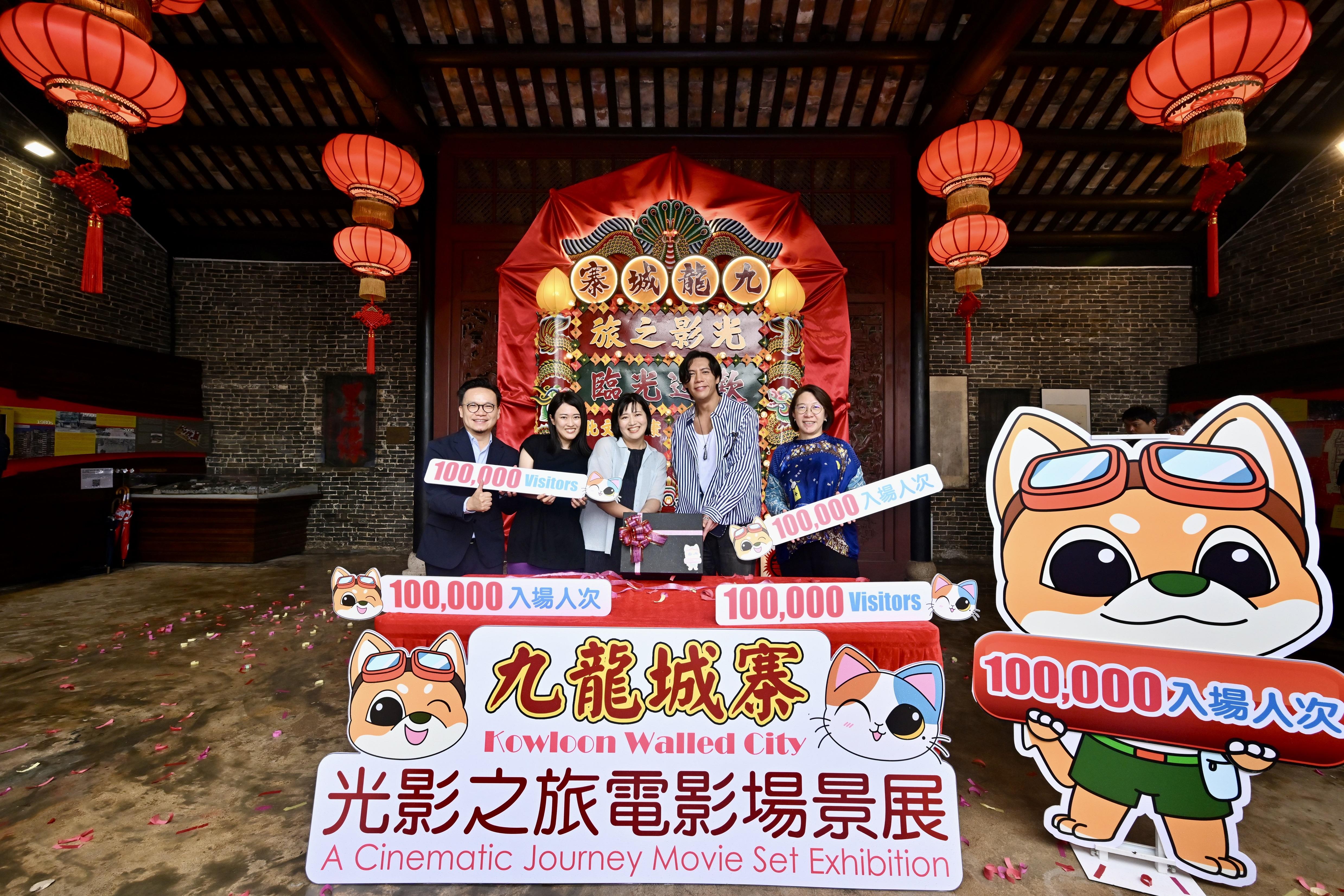 圖示康樂及文化事務署助理署長（康樂事務）馮妙玲（右一）、文創產業助理專員兼香港電影發展局秘書長麥聖希（左一）和《九龍城寨之圍城》演員張文傑（右二），向第十萬名參觀者（中）送上紀念品。(政府新聞處)