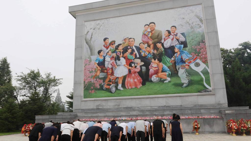 北韓人民向金正日及金日成的畫像致敬。(美聯社)