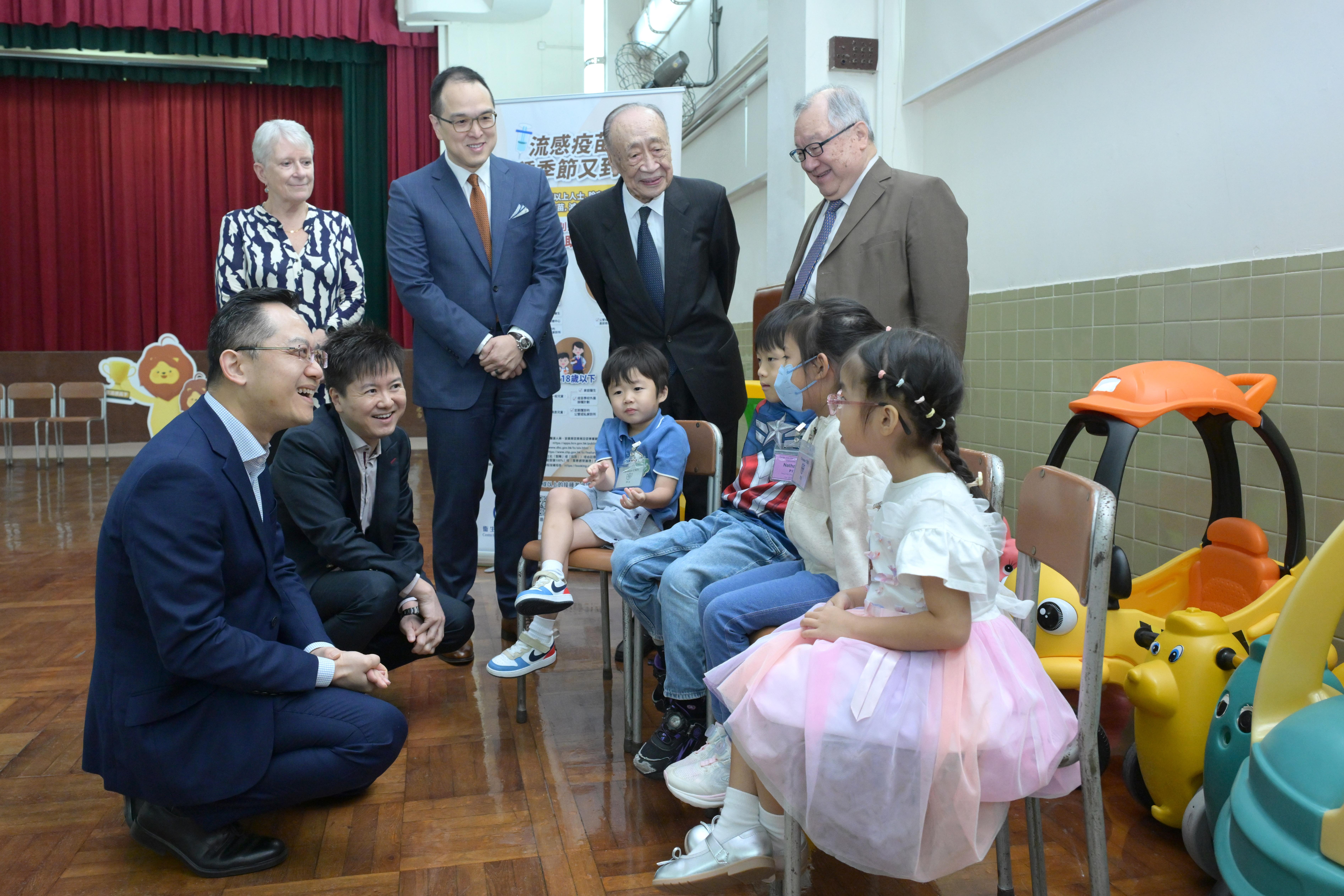 圖示林文健及徐樂堅與準備接種季節性流感疫苗的學生聊天。(政府新聞處)