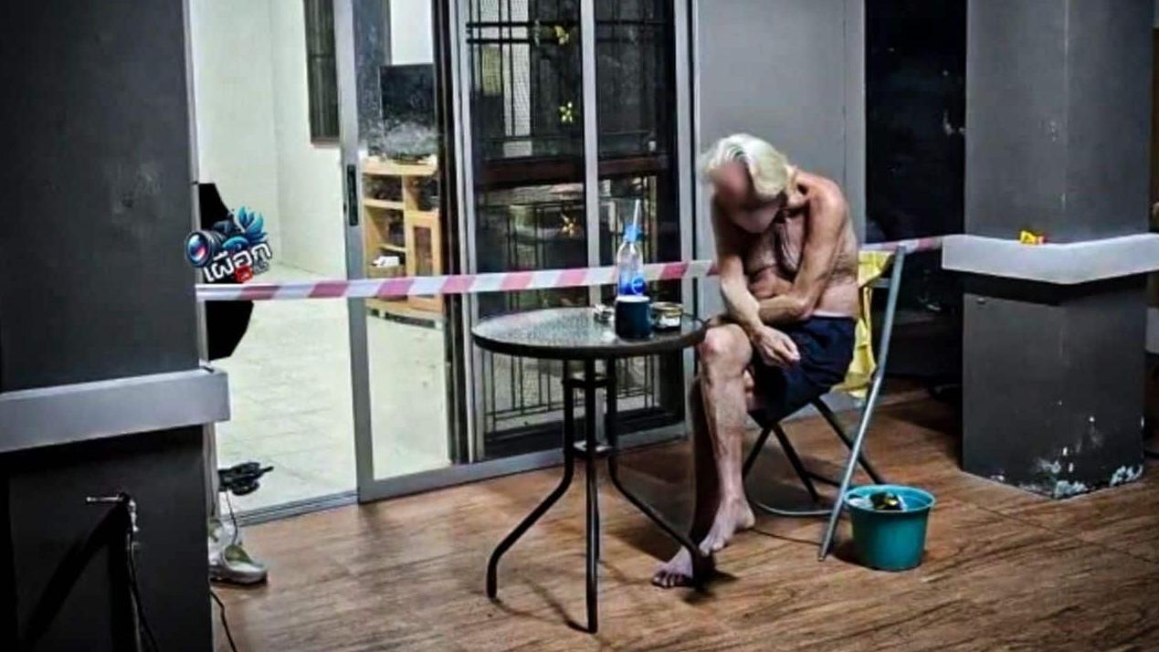 警方封鎖住處調查，失明德籍老翁坐在屋外， 為妻子輕生哀傷。(互聯網)