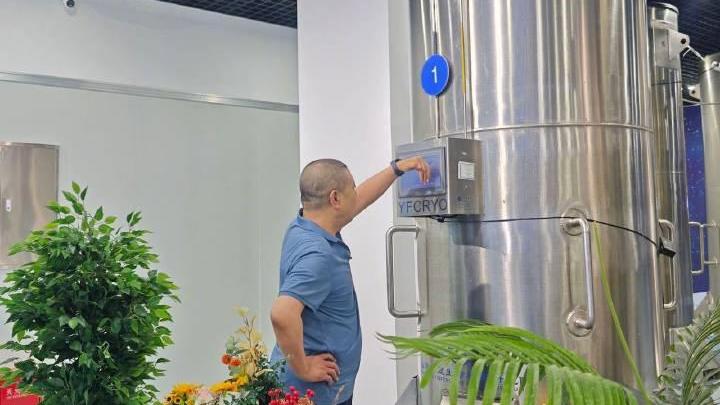 桂軍民站在儲存着癌逝妻展文蓮的液態氮罐前。（圖／翻攝南方周末）