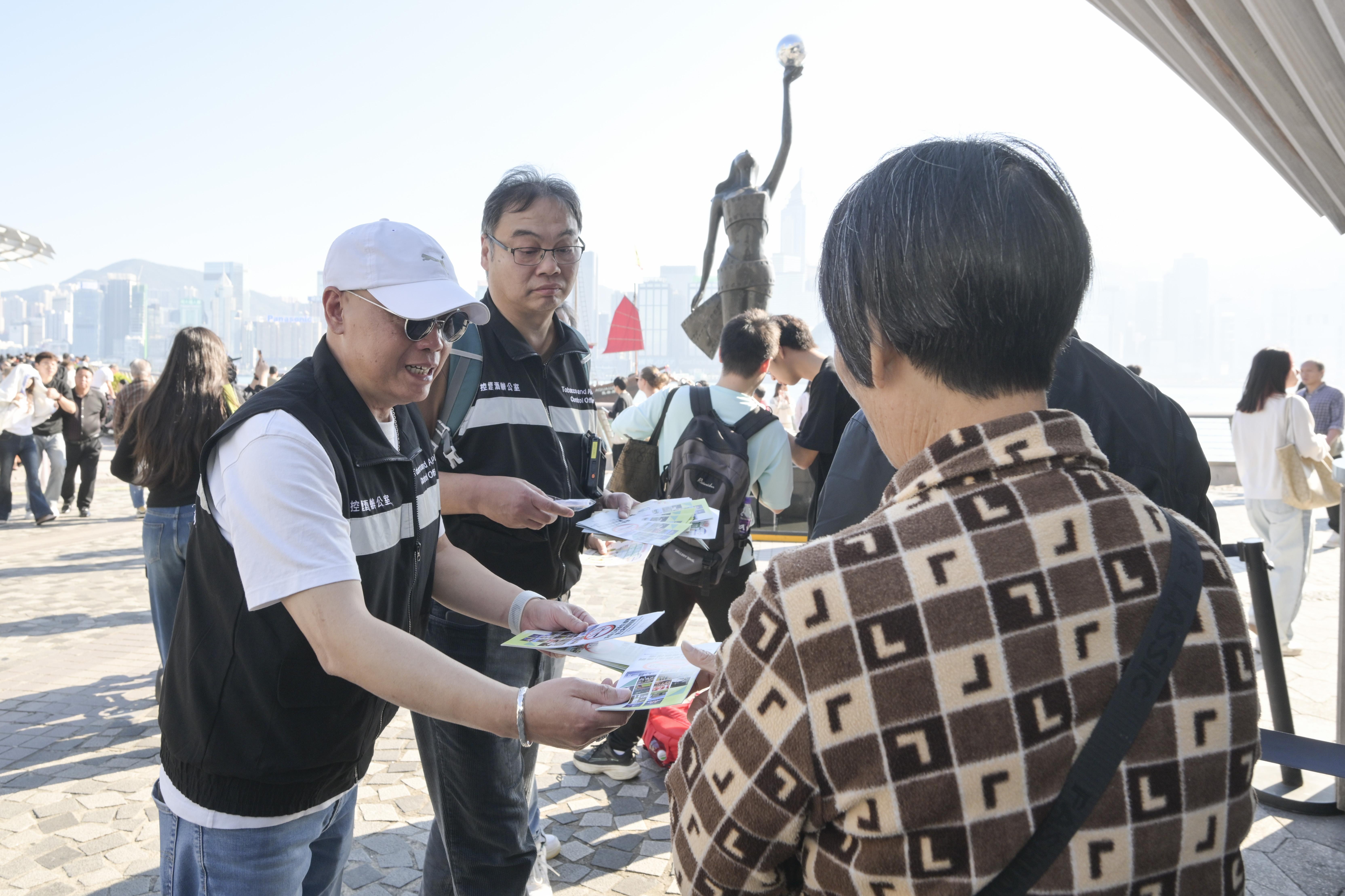 圖示控煙酒辦人員於尖沙咀向旅客派發有關控煙措施的宣傳單張。(政府新聞處)